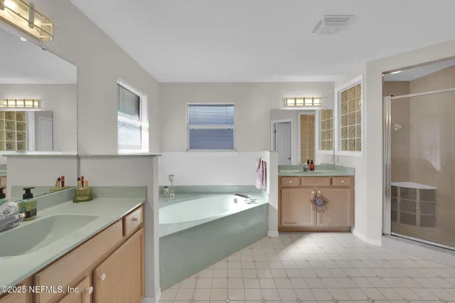 a spacious bathroom with a tub sink shower and mirror