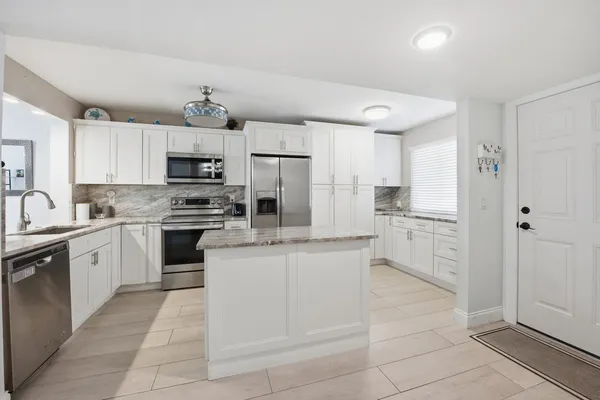 a kitchen with kitchen island granite countertop stainless steel appliances cabinets and a sink
