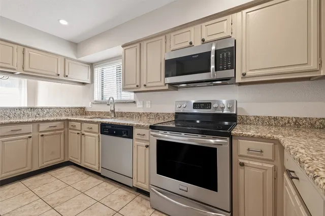 a kitchen with granite countertop white cabinets stainless steel appliances and a counter space