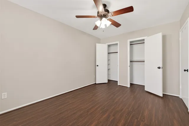 an empty room with wooden floor and ceiling fan