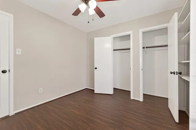 an empty room with wooden floor and a ceiling fan