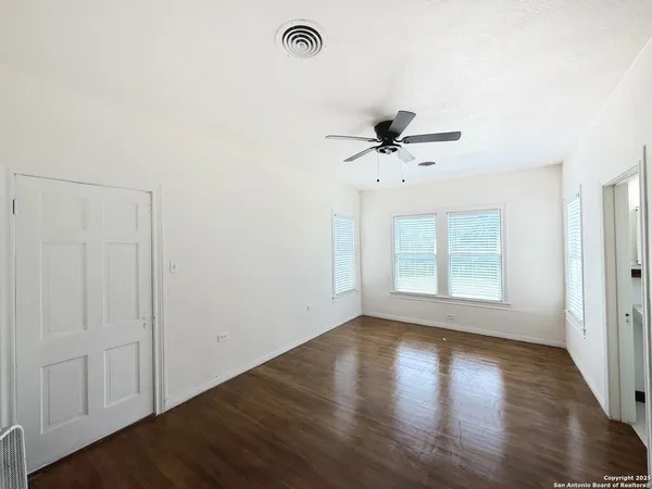 a view of empty room with wooden floor and fan