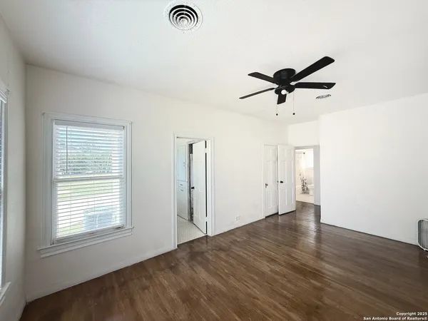 an empty room with a window and a ceiling fan