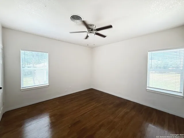 an empty room with wooden floor and ceiling fan