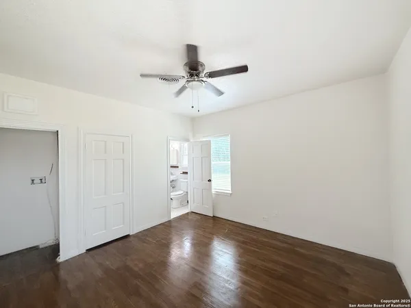 an empty room with wooden floor and a ceiling fan