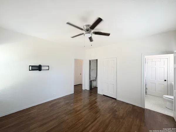 an empty room with wooden floor and fan