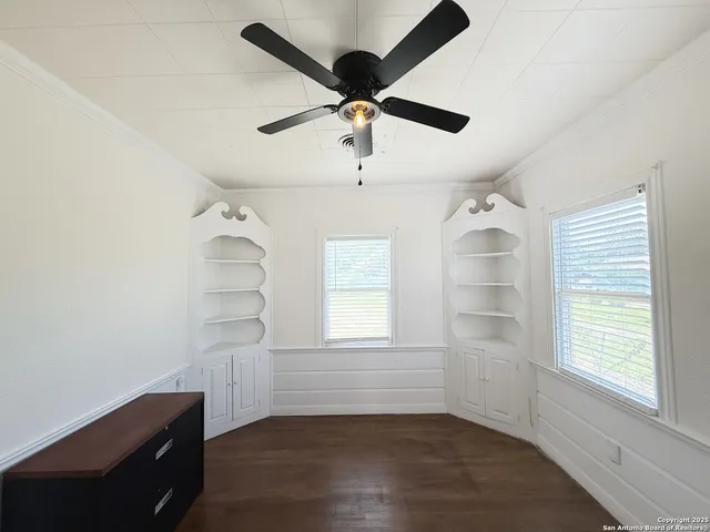 a view of an empty room with a window and wooden floor