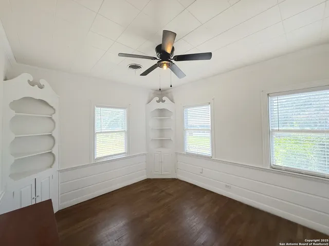 an empty room with wooden floor closet and windows