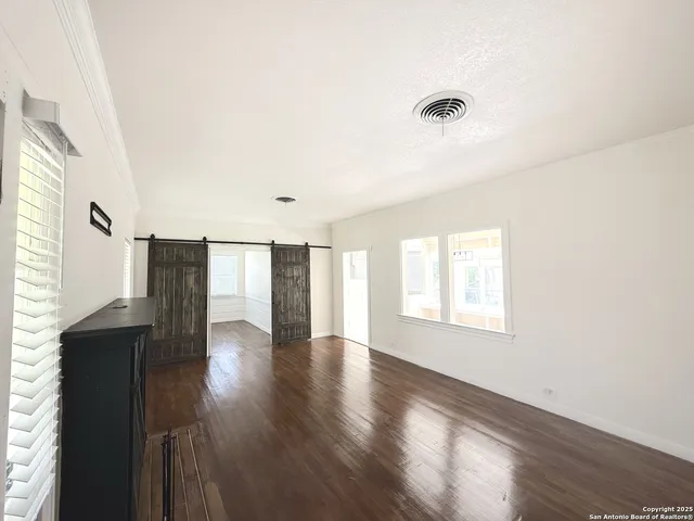 a view of an empty room with wooden floor and a window