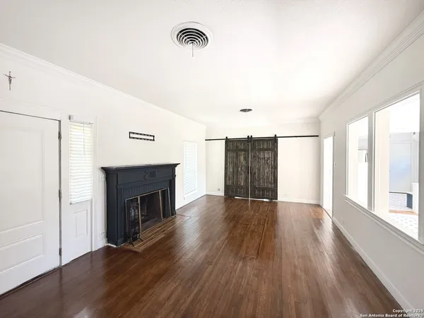 an empty room with wooden floor fireplace and windows