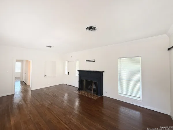 an empty room with wooden floor fireplace and window