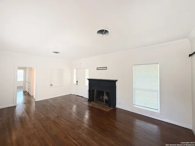 an empty room with wooden floor fireplace and window