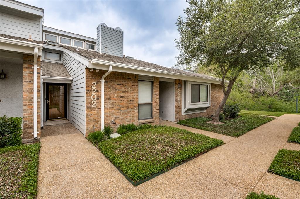 17490 Meandering Way, Unit 2202 Dallas, TX 75252 - Photo 1 of 24 Brick and siding exterior featuring an exposed aggregate walkway, an established tree, and groundcover landscaping