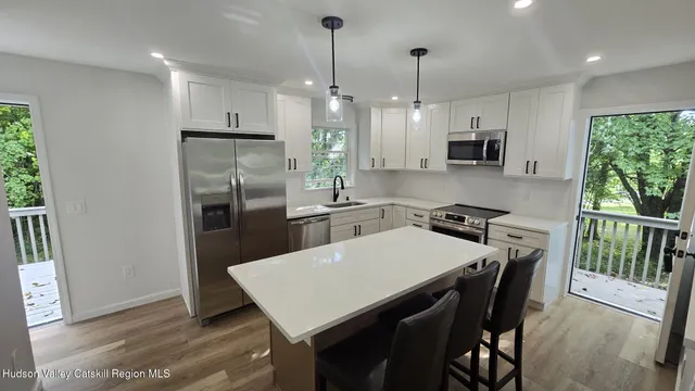 a kitchen with stainless steel appliances a table chairs refrigerator and microwave