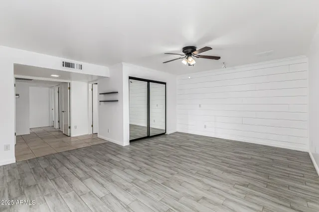 a view of empty room with wooden floor and fan