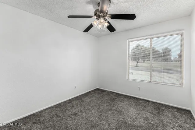an empty room with a window and a ceiling fan