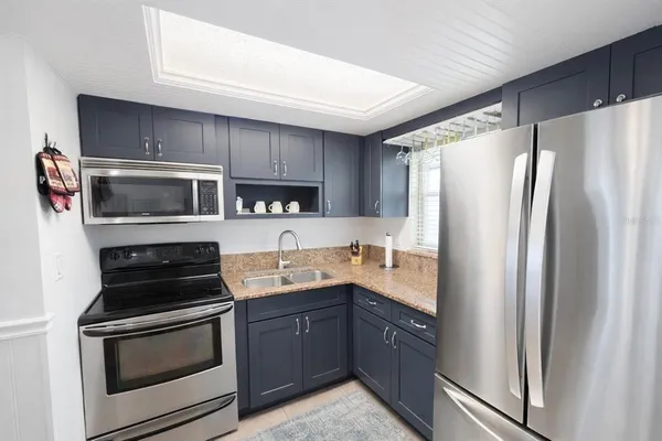 a kitchen with granite countertop a refrigerator stove and microwave