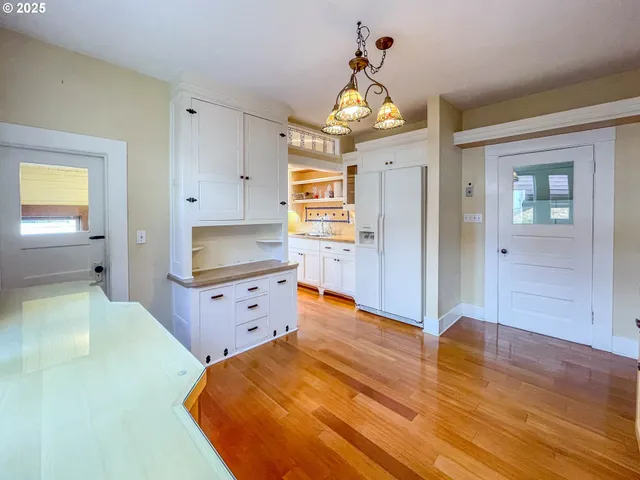 a large kitchen with wooden floor and stainless steel appliances