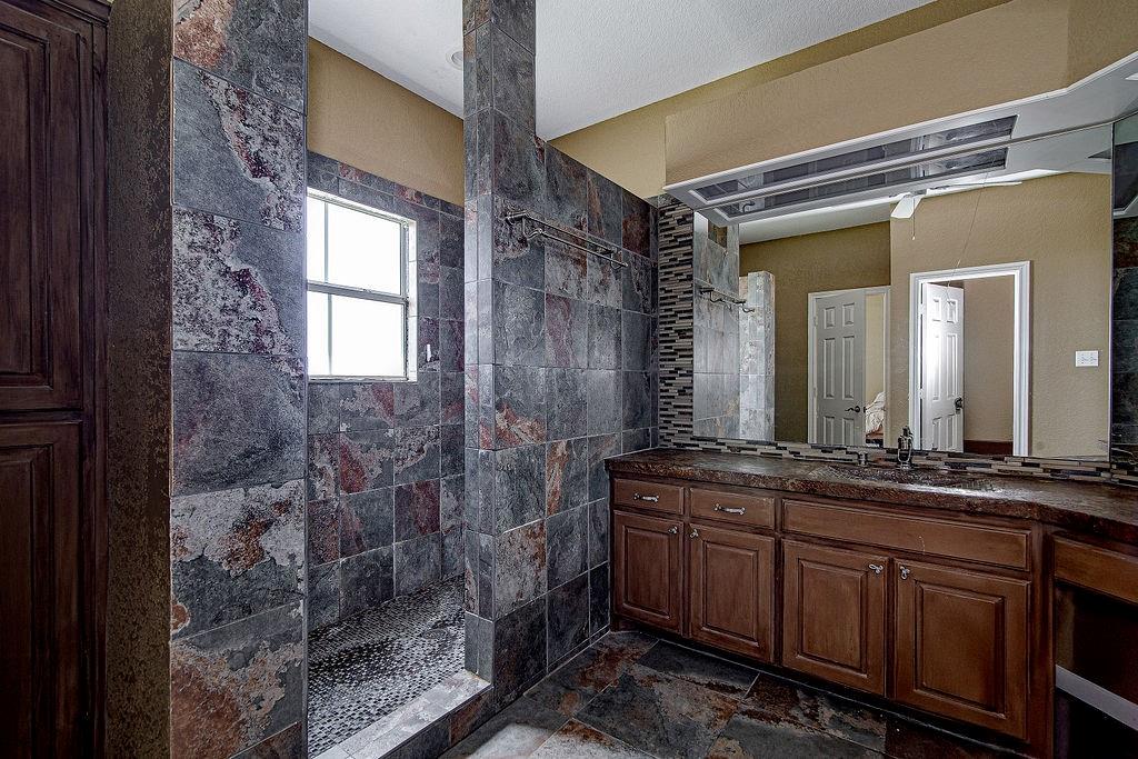 9801 Bellechase Road Granbury, TX 76049 - Photo 32 of 40 a spacious bathroom with a granite countertop sink a mirror and a shower