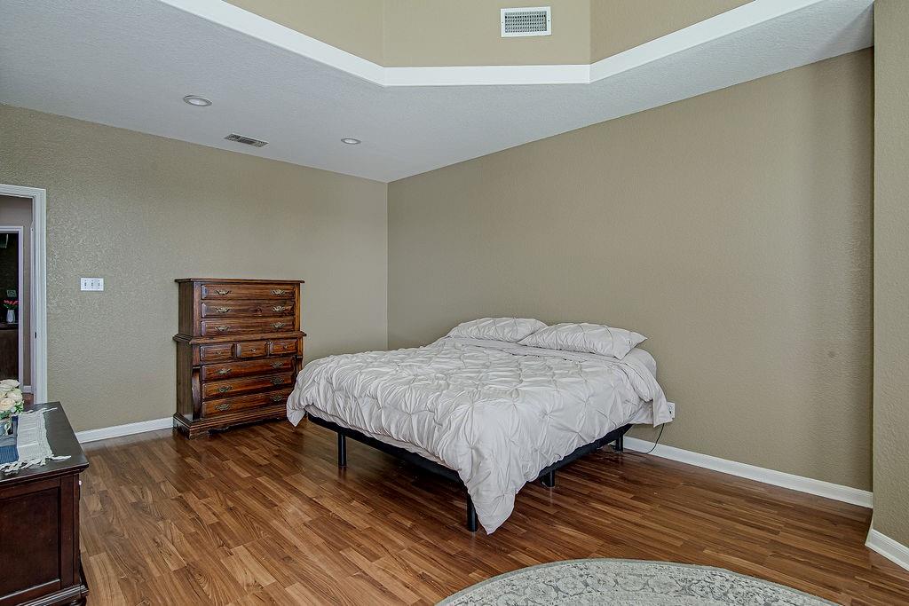 9801 Bellechase Road Granbury, TX 76049 - Photo 35 of 40 a bedroom with a bed and wooden floor