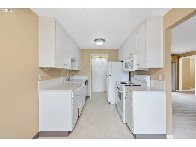 a kitchen with stainless steel appliances a sink a stove a refrigerator cabinets and a window