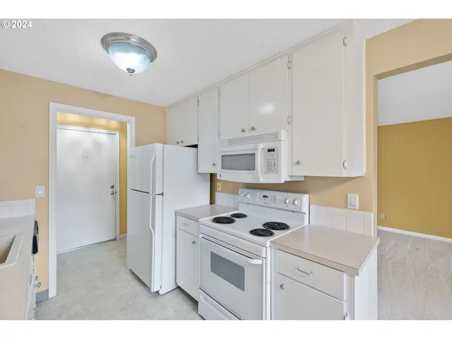 a kitchen with a refrigerator a stove cabinets and living room view
