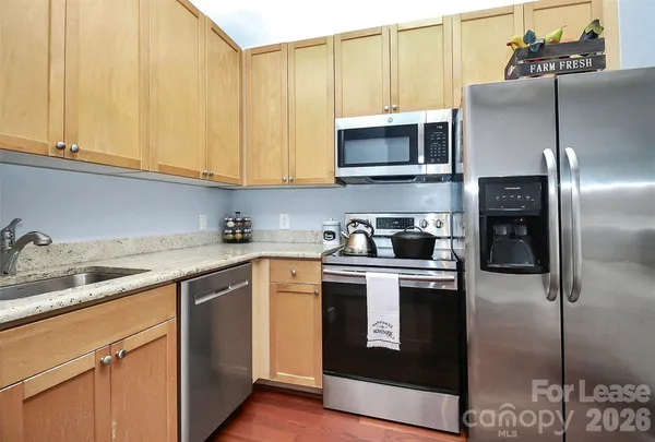 a kitchen with stainless steel appliances granite countertop a refrigerator a sink a stove and white cabinets
