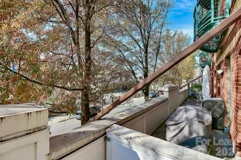 a view of a balcony with wooden fence and two of trees