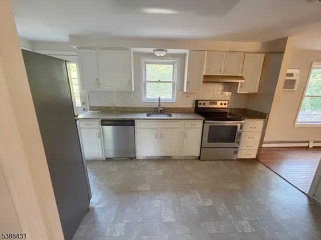 a kitchen with stainless steel appliances a sink a stove a microwave a refrigerator a window