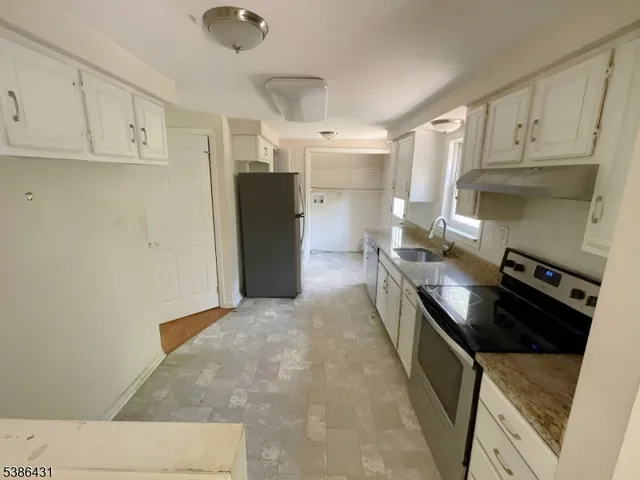 a kitchen with stainless steel appliances granite countertop a refrigerator a stove and white cabinets