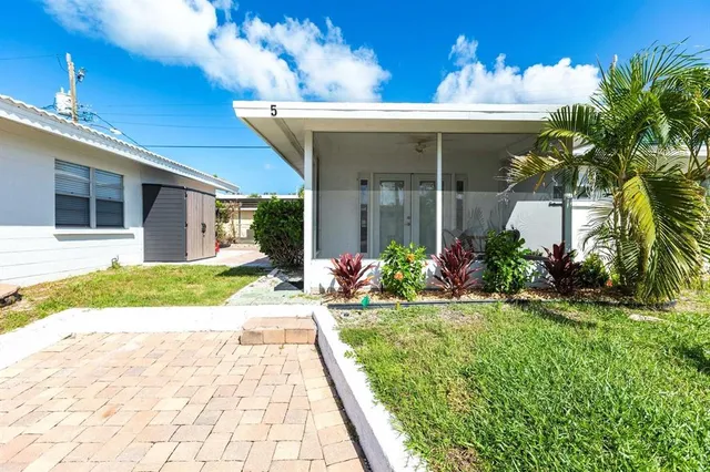 a front view of a house with a yard and potted plants