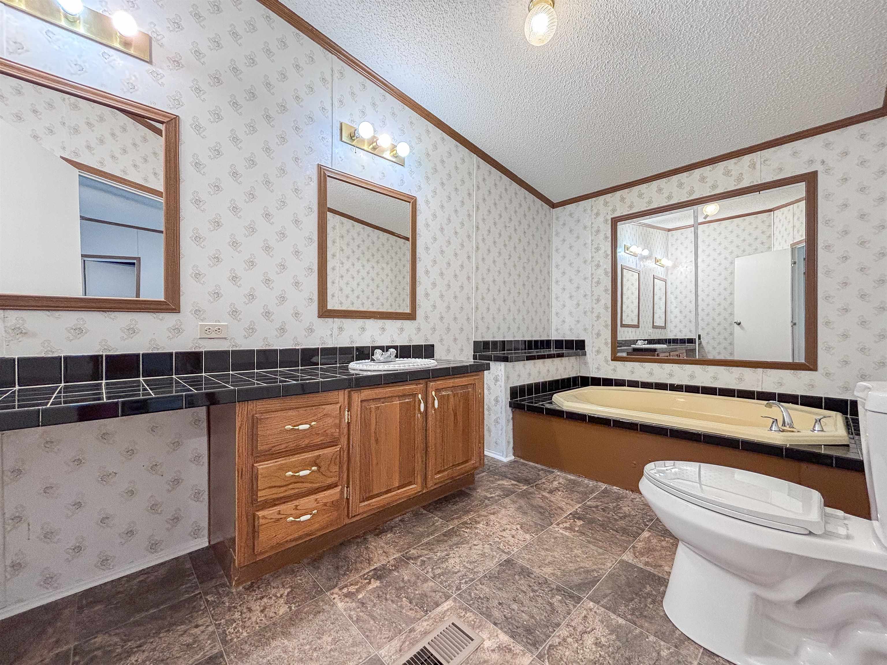 2847 Holly Grove Road Covington, TN 38019 - Photo 18 of 36 Bathroom featuring a built-in tub with tile surround, wood-finish vanity with dual sinks, and tile flooring