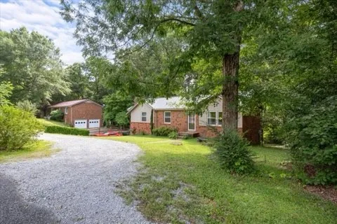 a front view of a house with a yard and a large tree