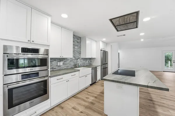 a kitchen with stainless steel appliances white cabinets and wooden floor