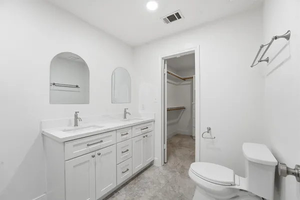a bathroom with a toilet sink double vanity and mirror