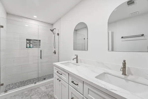 a bathroom with a double vanity sink mirror and shower