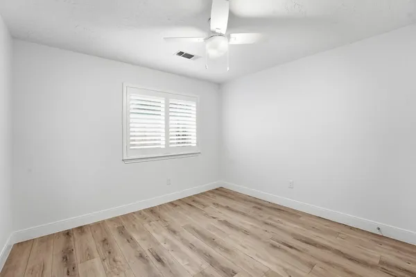 an empty room with a window and a ceiling fan