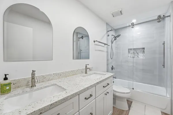 a bathroom with a granite countertop sink a toilet and shower