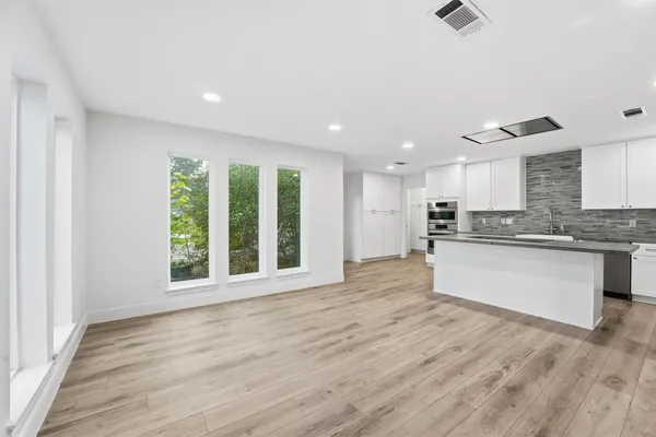 a large kitchen with stainless steel appliances granite countertop a stove a sink and a large window