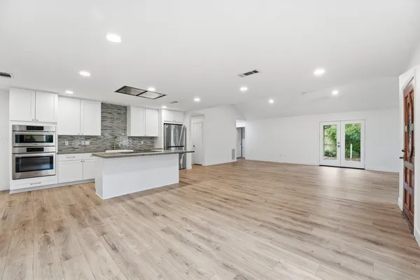 a large kitchen with stainless steel appliances kitchen island a large counter top and a stove top oven