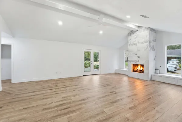 an empty room with wooden floor and windows