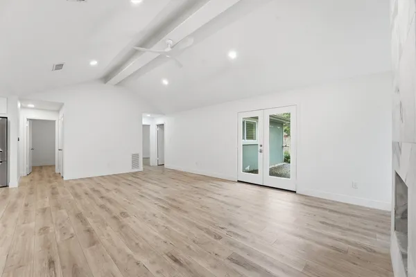 a view of an empty room with wooden floor and a window