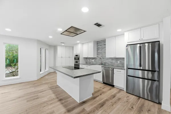 a kitchen with stainless steel appliances granite countertop a refrigerator a sink dishwasher a stove and a refrigerator with wooden floor