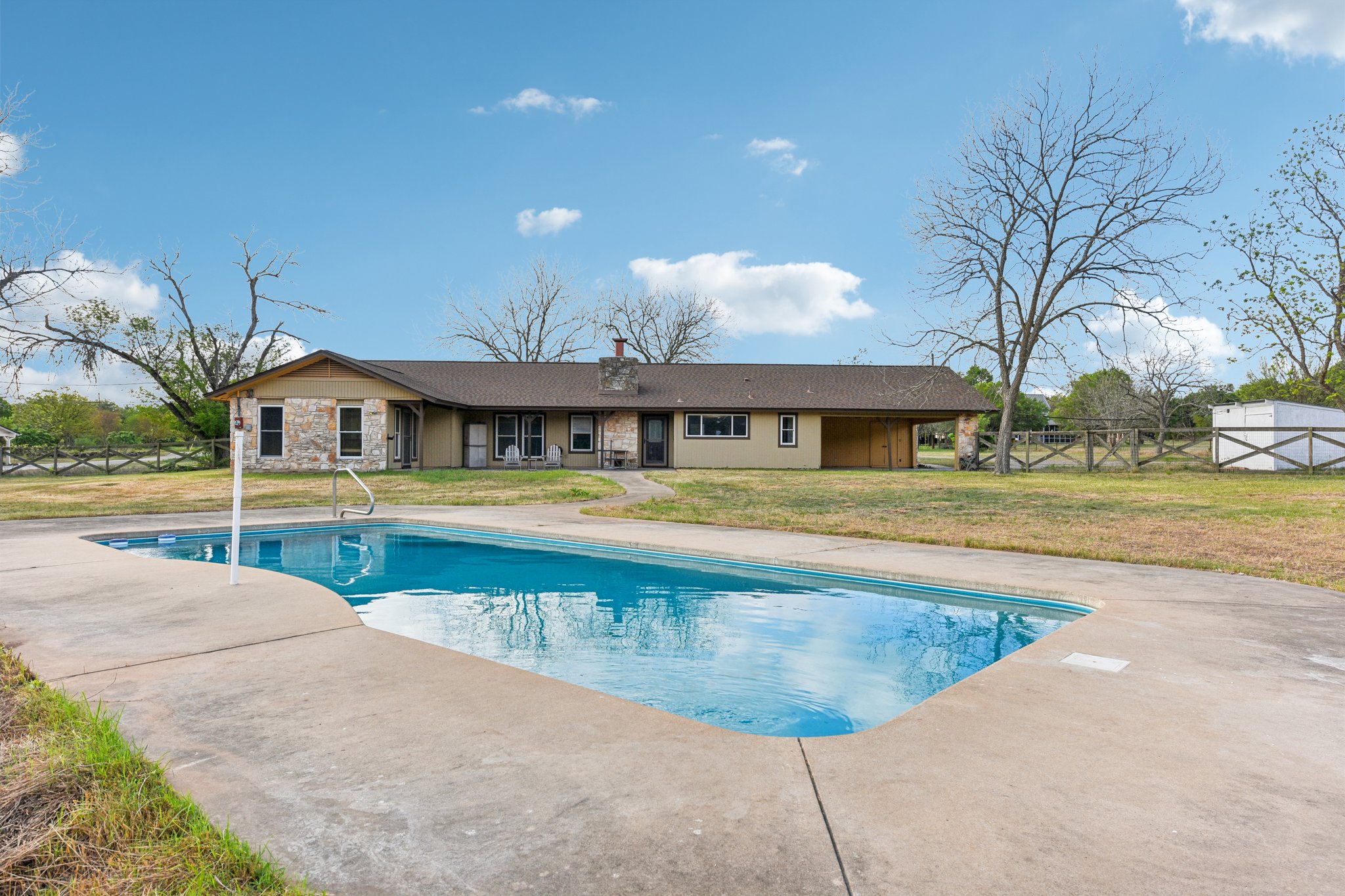 Rear view of property featuring a chimney, a patio area, and stone siding
