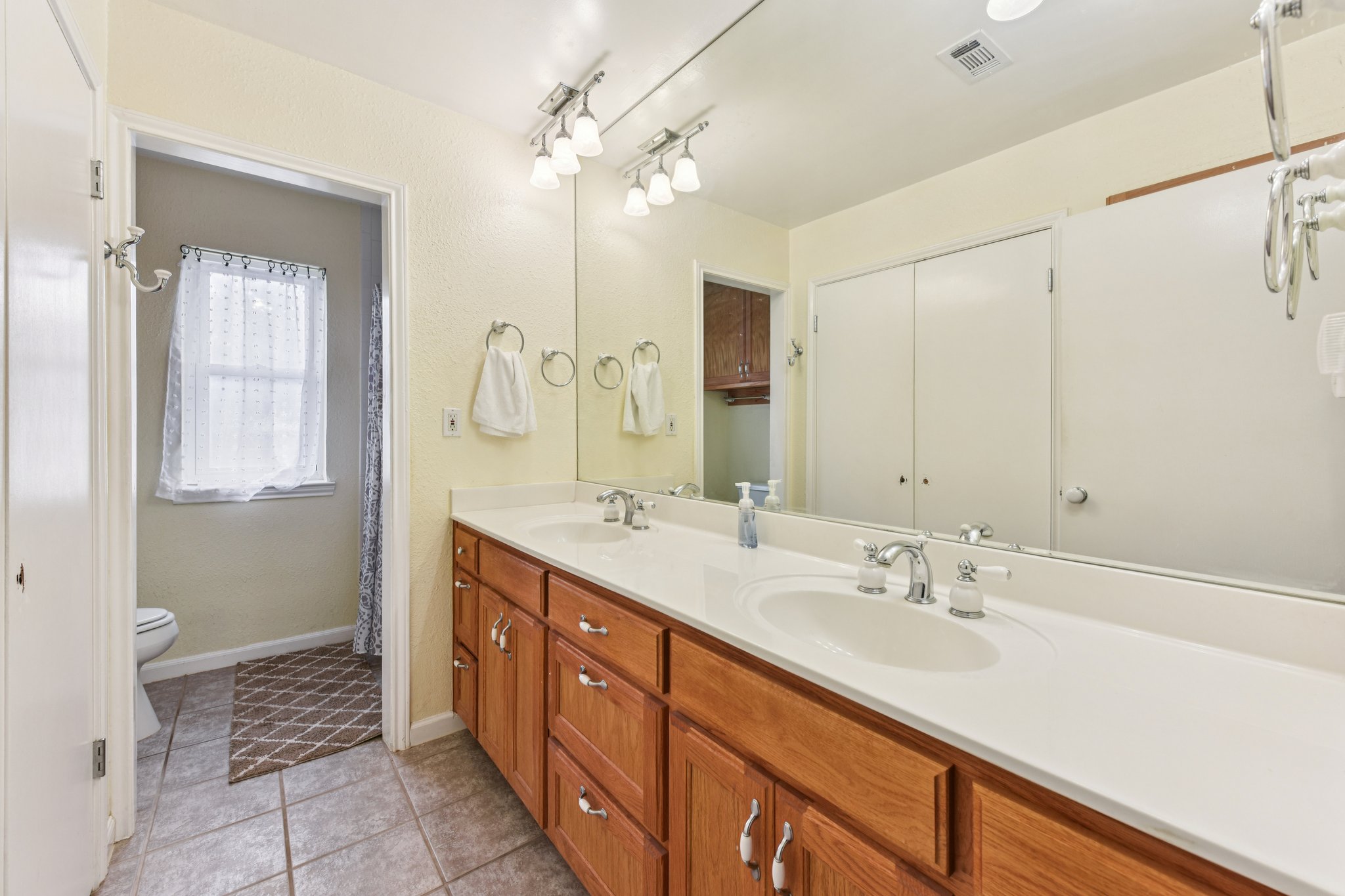 504 Buckaroo Trail Buda, TX 78610 - Photo 12 of 39 Full bathroom featuring double vanity, light tile patterned floors, and a shower with shower curtain
