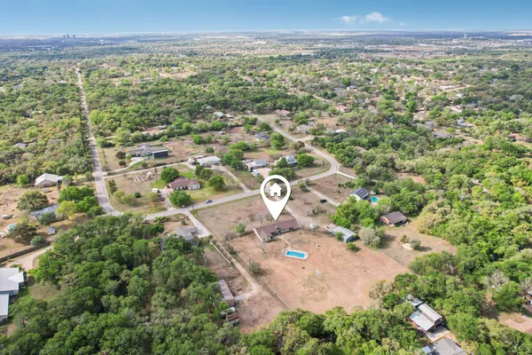 an aerial view of residential houses with outdoor space and trees