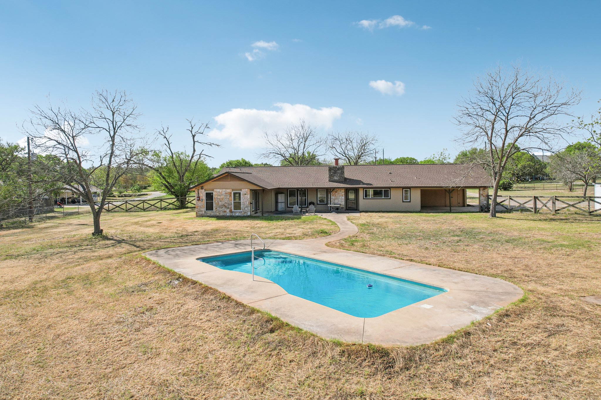 504 Buckaroo Trail Buda, TX 78610 - Photo 35 of 39 Back of house featuring a fenced backyard, an outdoor pool, a patio area, stone siding, and a chimney