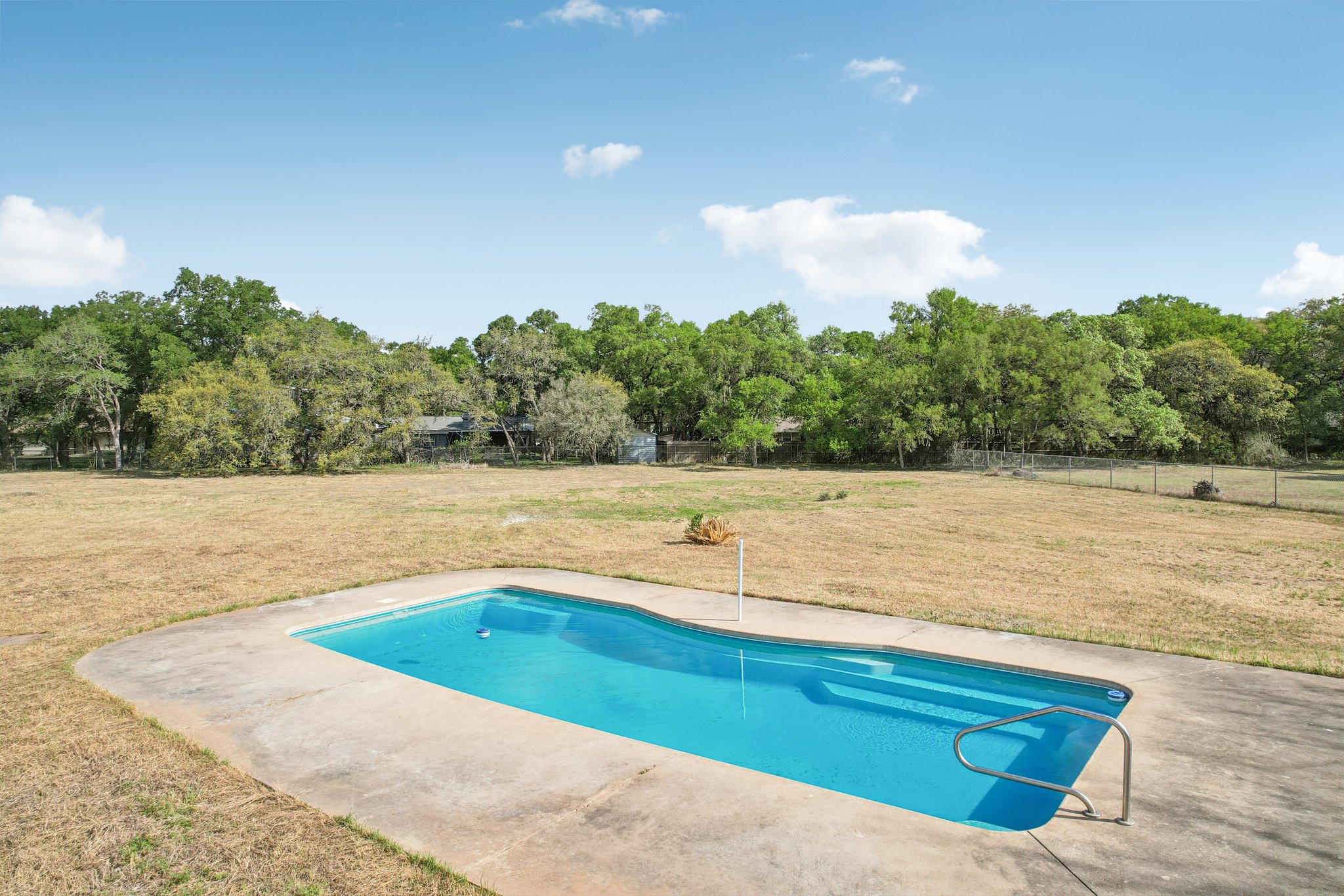 504 Buckaroo Trail Buda, TX 78610 - Photo 36 of 39 Outdoor pool featuring a patio area and view of wooded area
