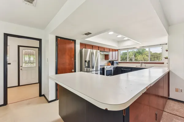 a kitchen with kitchen island a large counter top space appliances and windows