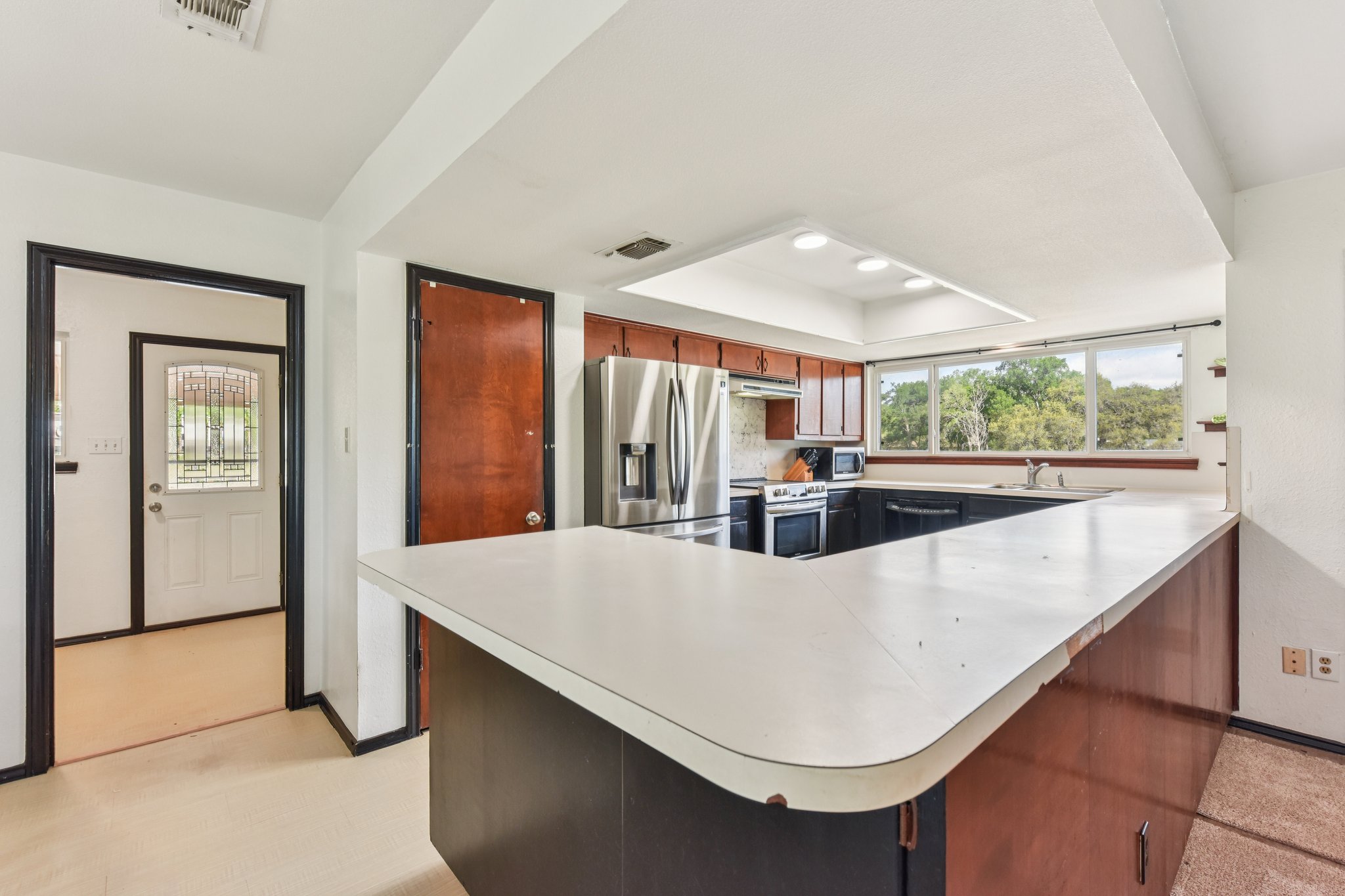 504 Buckaroo Trail Buda, TX 78610 - Photo 5 of 39 Kitchen with a peninsula, light countertops, stainless steel appliances, a tray ceiling, and recessed lighting
